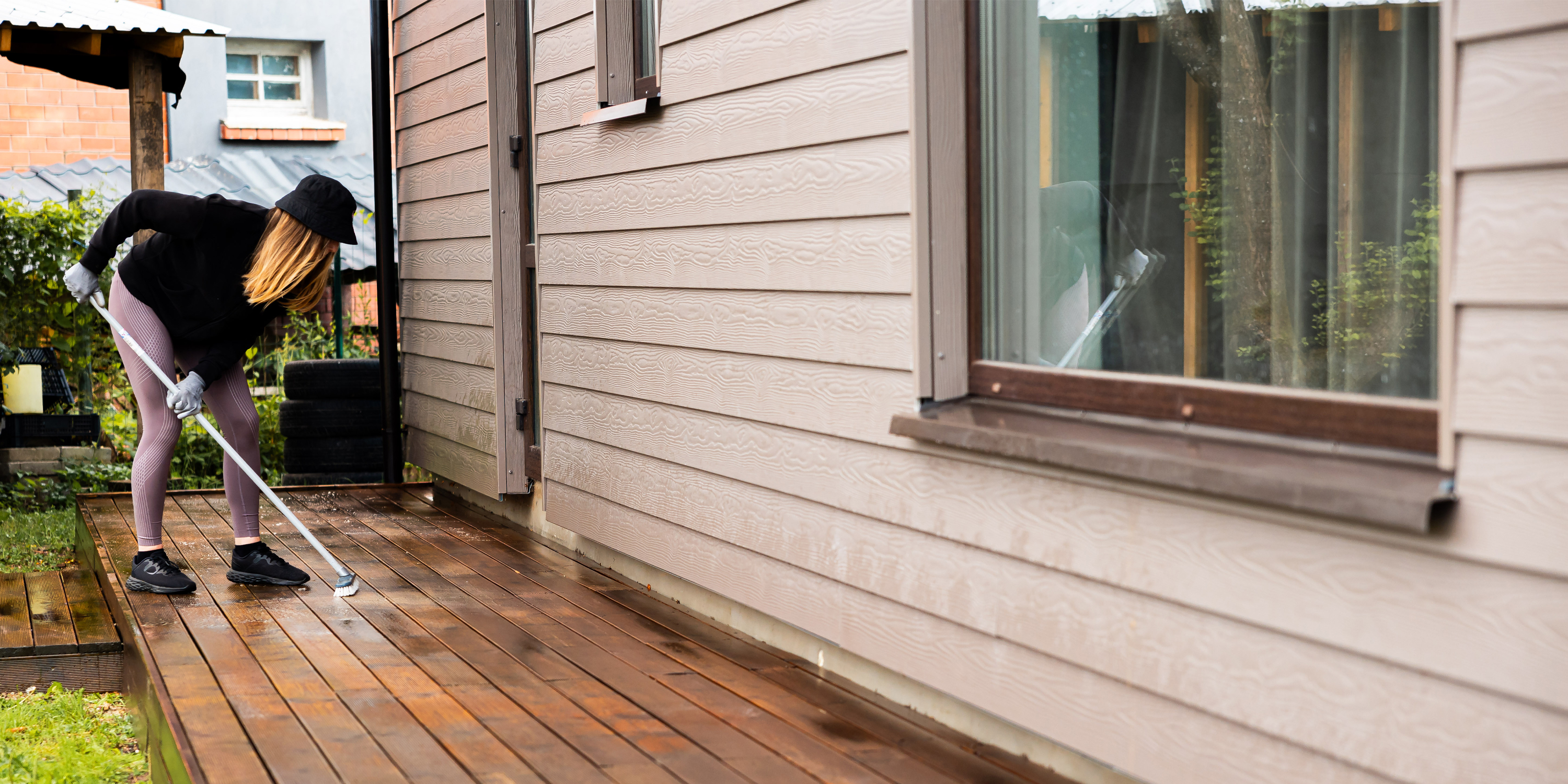 woman washes wooden terrace before painting it her modern private house3000x1500